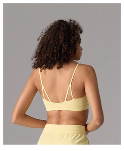 Détail des fines bretelles croisées du soutien-gorge de sport jaune au dos sans couture