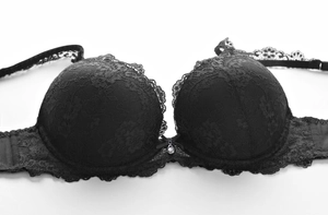 Détail d'un soutien-gorge en dentelle noire avec broderie florale et petit pendentif