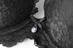 Détail d'un soutien-gorge en dentelle avec nœud satiné et pendentif cristal en goutte