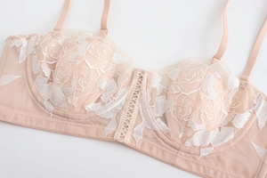 Close-up of pink lace bra with white rose embroidery and central lace-up ribbon detail