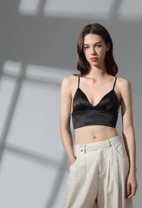 Detail of black silk satin bra with thin straps and deep V-neckline on model