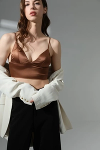 Detail of a brown satin v-neck camisole vest under an oversized white blazer for women