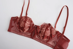 Detailed close-up of wine red lace bra with rose embroidery and mesh side wings