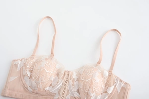 Detail of pink lace bra with white rose embroidery and delicate lace-up center knot