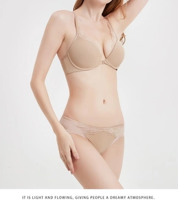 Dettaglio del reggiseno in pizzo beige con chiusura anteriore e ricami floreali