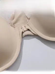 Dettaglio macro della chiusura frontale e del pizzo beige su reggiseno in tessuto liscio