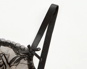Détail de dentelle florale noire délicate avec petit nœud et fine bretelle de soutien-gorge