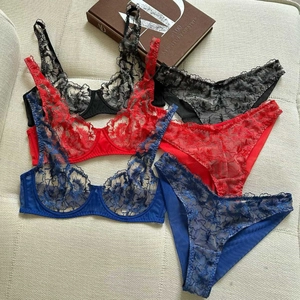 Three sets of lace lingerie in black, red, and blue displayed on a textured fabric