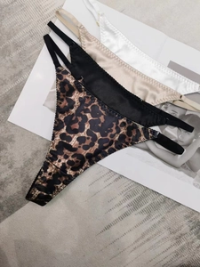 Flat lay of four satin thongs in leopard, black, gold, and white with thin side straps