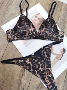 Flat lay view of leopard print satin lingerie set with thin black straps on wood floor