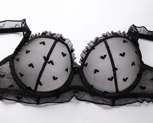 Detailed close-up of semi-transparent black mesh bra with heart pattern and lace ruffles