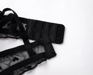 Detail of black lace bra back closure with four-row hooks and heart mesh fabric