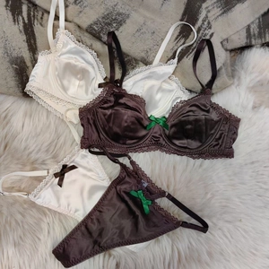 Detail view of satin lace bras and panties with delicate silk bows and eyelash trim