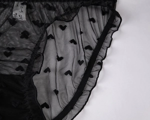 Detail of sheer black mesh panties with heart patterns and delicate ruffled edges