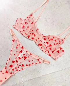 Flat lay detail of pink mesh lingerie set with red heart print and adjustable straps