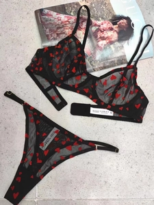 Flat lay of sheer black mesh lingerie set featuring red heart embroidery and lace details