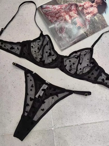 Flat lay of black lace lingerie set with mesh heart pattern on marble floor