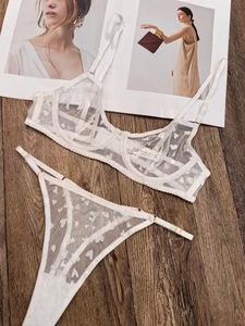 Flat lay of white lace lingerie set with heart mesh pattern and gold metal hardware detail