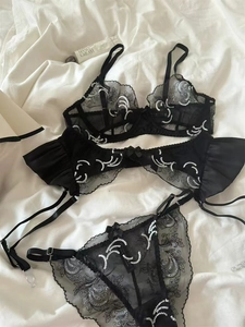 Detailed flat lay of black sheer lace lingerie set with silver embroidery and garter belt