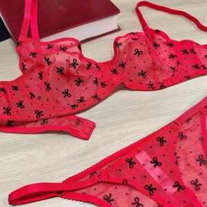 Detail of red mesh lingerie set with black bow patterns and delicate lace edges on wood