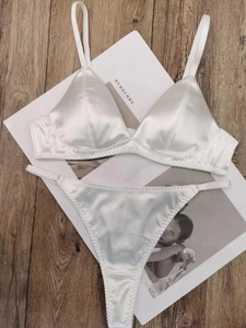 Gedetailleerde flat lay van witte satijnen lingerieset met kant op een houten vloer