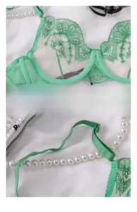 Detail of mint green lace bra cups with sheer embroidery and adjustable straps
