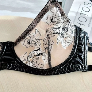 Close-up of black lace embroidery and shiny patent leather on sexy lingerie bra