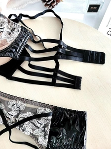 Detail of black lace lingerie set with floral embroidery and glossy patent leather panels