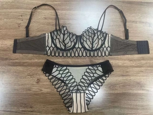 Détail d'un ensemble de lingerie en dentelle noire avec mesh géométrique sur bois