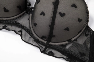 Detail of black mesh bra featuring flocked heart patterns and delicate lace ruffles