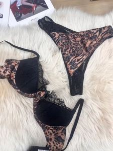 Detailed view of leopard print satin lingerie with black lace trim on a white carpet