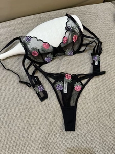 Detail view of black sheer lace bra with pink and purple pineapple embroidery