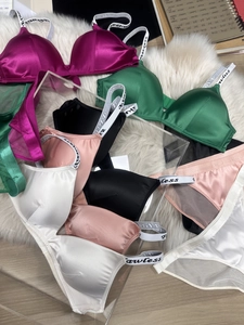Detail of satin bras with Lawless letter straps in various colors on white fur