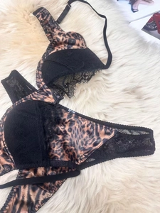 Lace detail of leopard print bra and panty set on white faux fur background