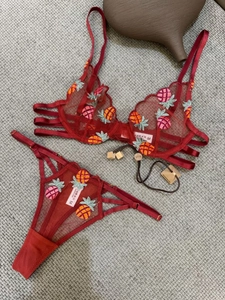 Detail of red mesh lingerie set with intricate yellow and green pineapple embroidery