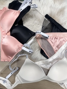 Flat lay of satin lingerie sets with logo straps in pink, black, and white colors