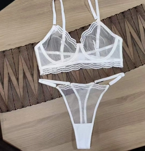 Flat lay of white mesh lace lingerie set with wired bra and thong on wooden floor