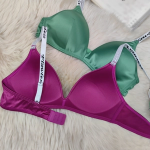 Detail view of satin bras with letter print straps and triple hook closure on plush rug