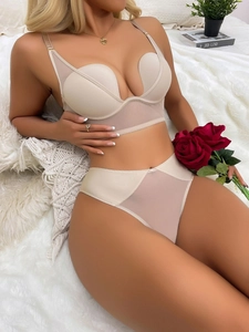 Detail showing elegant nude mesh push-up bra and high-waisted panty set on a white rug