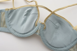 Detail view of seamless light blue bra with soft support and fine cross strap stitching