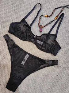 Flat lay of black sheer lace lingerie set with floral embroidery and satin bows