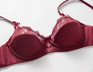 Close-up of deep red satin bra with delicate eyelash lace trim and bow details