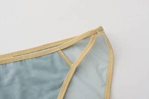 Detail view of light blue mesh fabric with beige elastic webbing and zigzag stitching