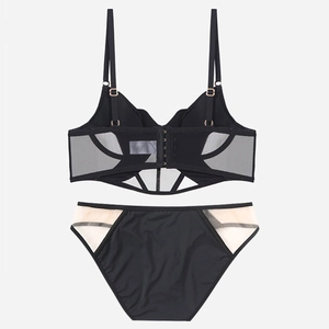 Dettaglio del set lingerie a corsetto in rete nera con pannelli trasparenti e ganci