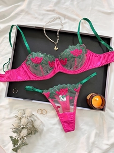 Dettaglio di ricamo floreale rosso su set lingerie con spalline in raso verde