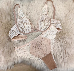 Détail de l'ensemble de lingerie en dentelle florale blanche sur tapis en peluche
