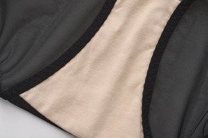 Détail du tissu en maille noire avec doublure en coton beige et coutures en zigzag