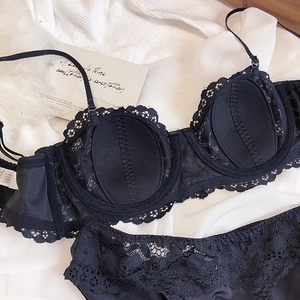 Flat lay of black lace lingerie set with 1/2 cup bra and matching panties on white fabric