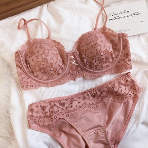 Flat lay of pink lace lingerie set including underwire bra and matching panties on white cloth