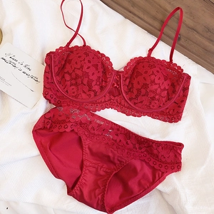Detail of red lace lingerie set with semi-cup bra and matching panties on a soft white rug